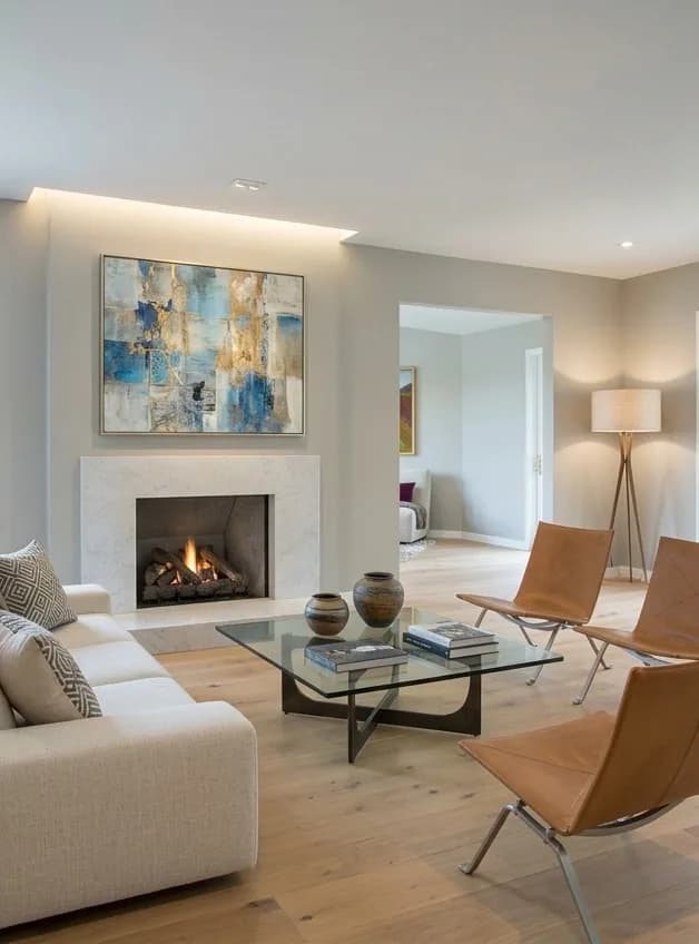 After: the same room with a rebuilt ceiling and concealed lighting, a stone fireplace surround, an oak floor and low contemporary seating.
